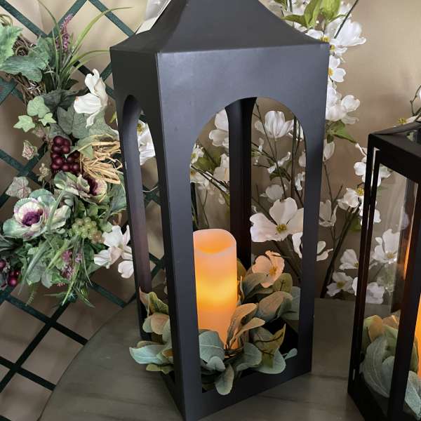 Black lantern with a glowing candle and white floral accents