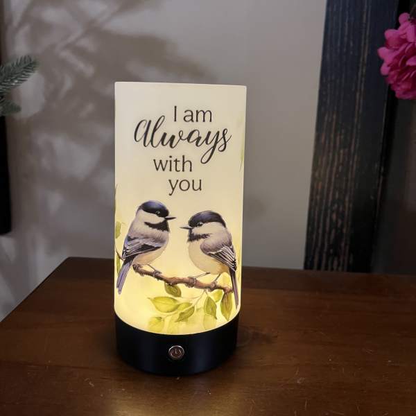 Lit memorial candle with two birds and the words "I am always with you"