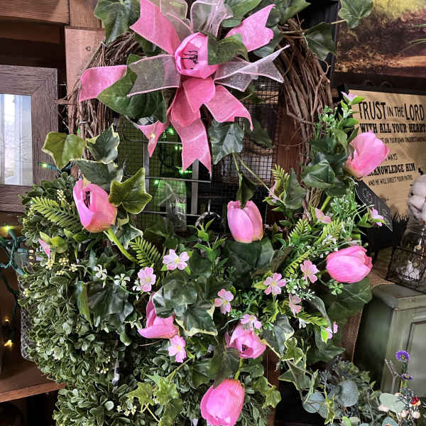 Pink tulips and ivy arranged on a grapevine wreath with a ribbon bow