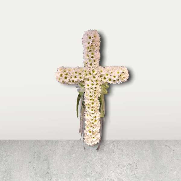 White daisy cross with ribbon accents on a plain wall