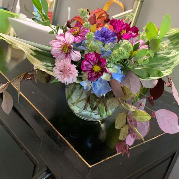 Mixed bouquet of pink, blue, and purple flowers in a glass vase
