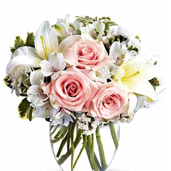 Pink roses and white lilies arranged in a clear glass vase