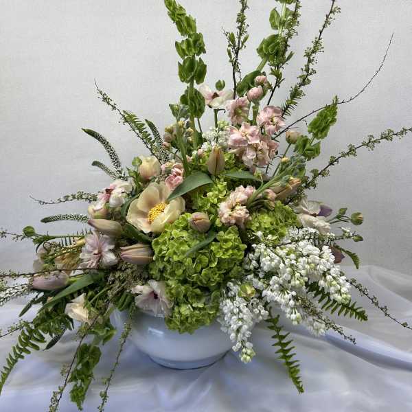 Large pastel floral arrangement in a white bowl vase