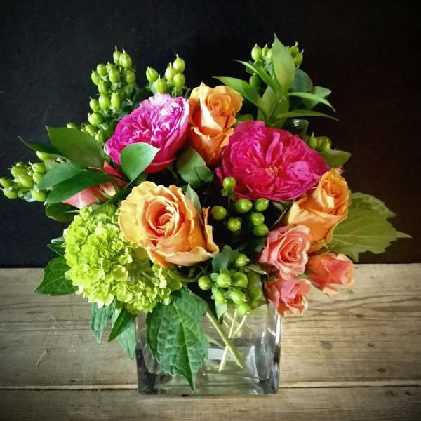 Colorful bouquet of roses and hydrangea in a clear square vase