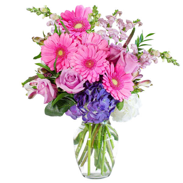 Mixed bouquet of pink gerbera daisies, lavender roses, and purple hydrangeas in a clear glass vase