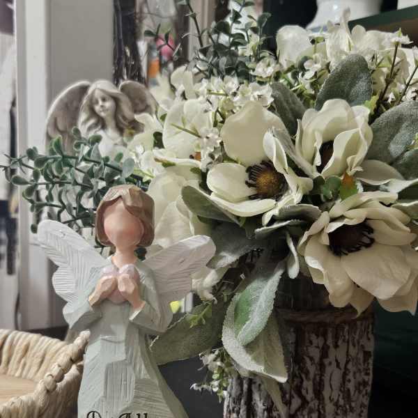 White floral arrangement with an angel figurine and a carved "Do All Things With Love" statue