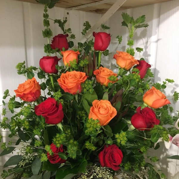 Bouquet of red and orange roses with greenery in a vase