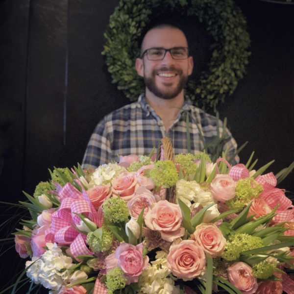 Large basket arrangement of pink roses and white blooms with gingham ribbons