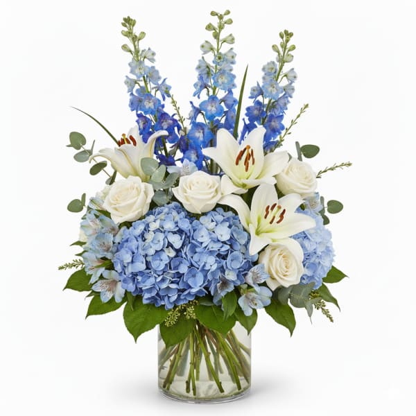 Blue hydrangeas, white roses, and lilies in a glass vase