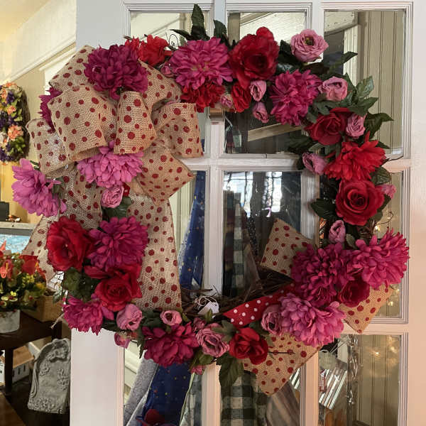 Pink and red floral wreath with burlap polka-dot ribbon on a white door