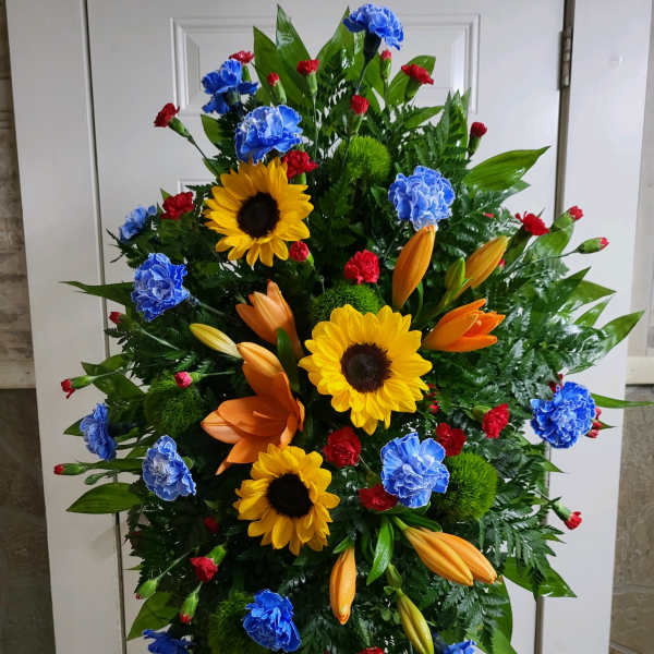 Standing floral spray with sunflowers, lilies, and carnations in bright colors