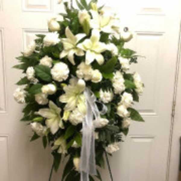 White floral standing spray with lilies and carnations on a ribboned easel
