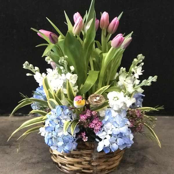 Basket arrangement with pink tulips and blue hydrangeas