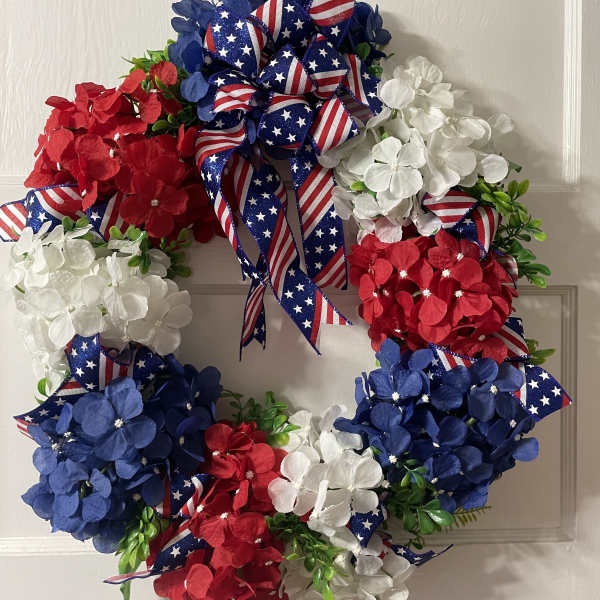 Patriotic wreath with red, white, and blue flowers and ribbon