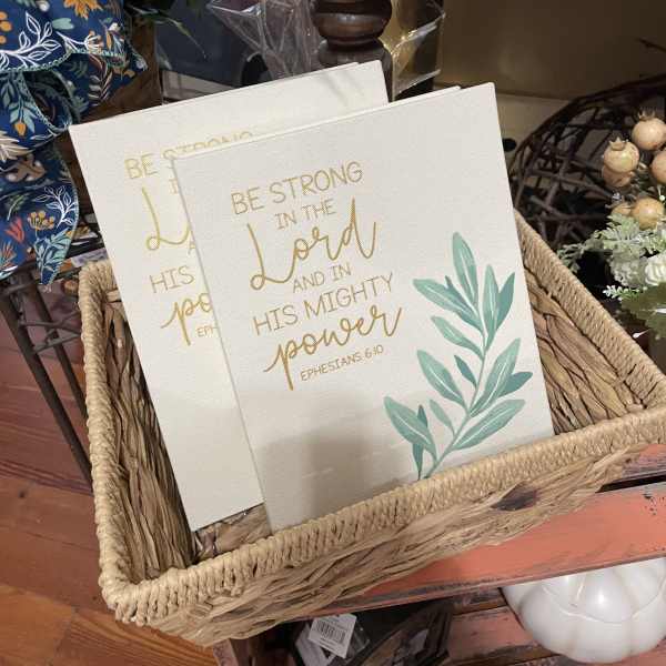 Two decorative canvas signs in a woven basket with gold lettering