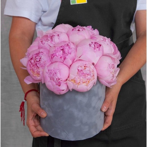Pink peonies arranged in a gray hatbox