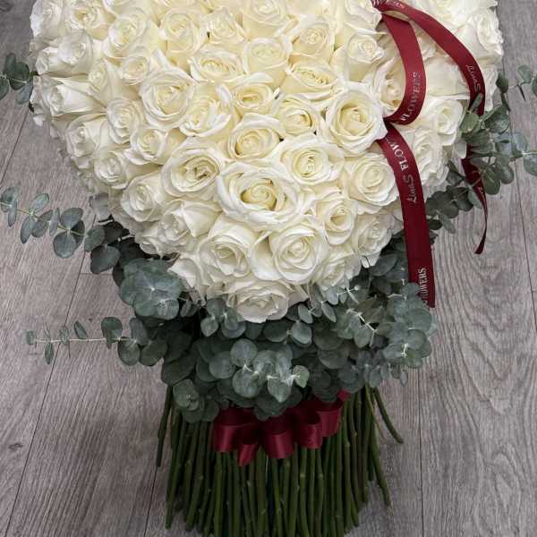 Heart-shaped bouquet of white roses with eucalyptus and a red ribbon