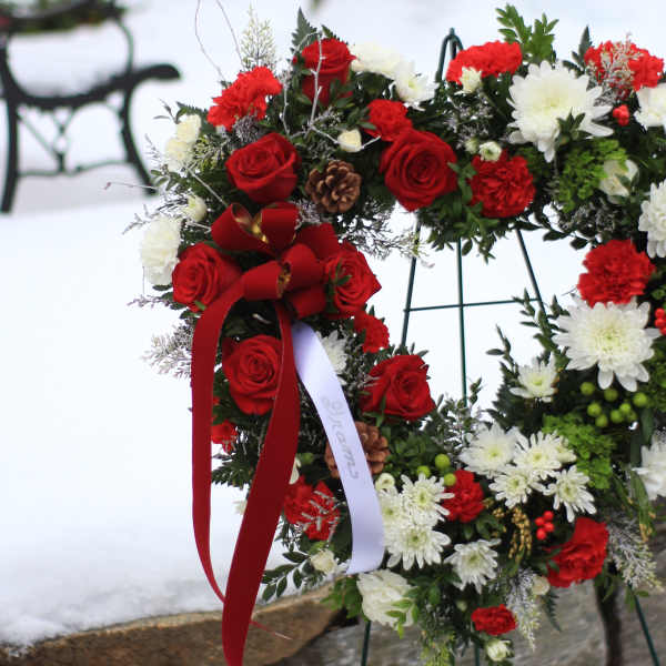 Floral wreath with red roses, white chrysanthemums, and a red ribbon