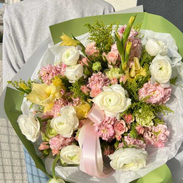Bouquet of white and pink flowers wrapped in green paper with a pink ribbon