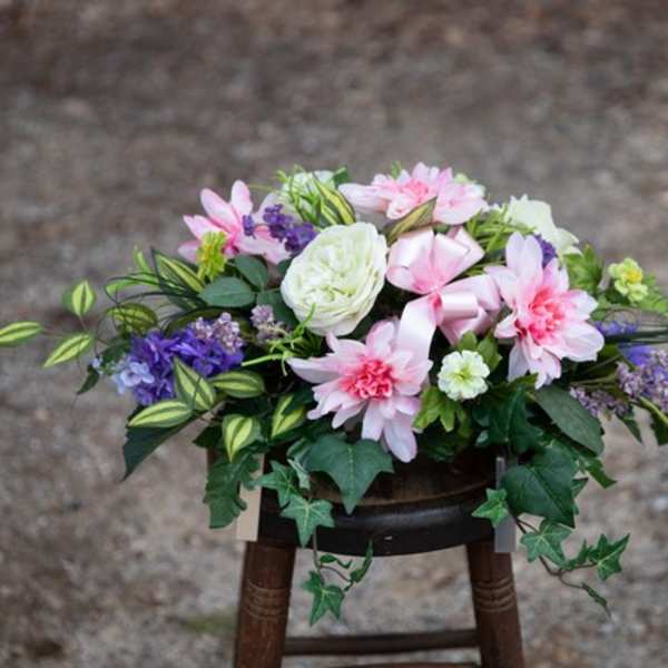 Pink and white floral arrangement with purple accents in a low container