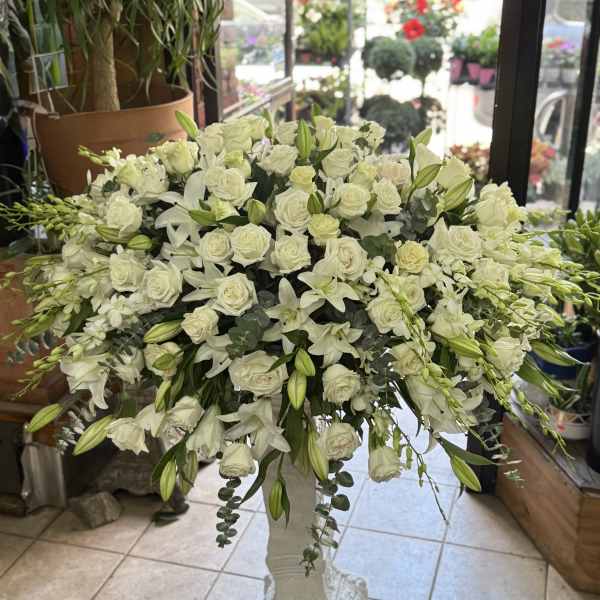 Large white floral arrangement in a pedestal vase