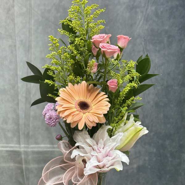 Mixed bouquet in a glass vase with pink roses, a peach gerbera, and white lilies