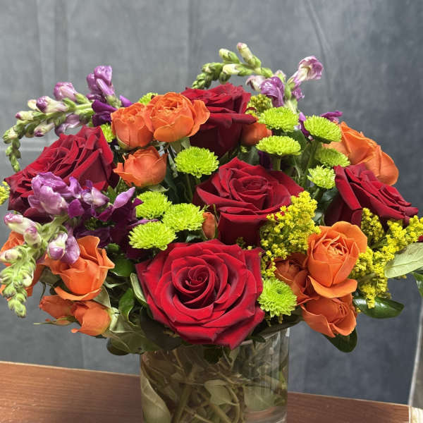 Mixed bouquet of red, orange, and purple flowers in a glass vase