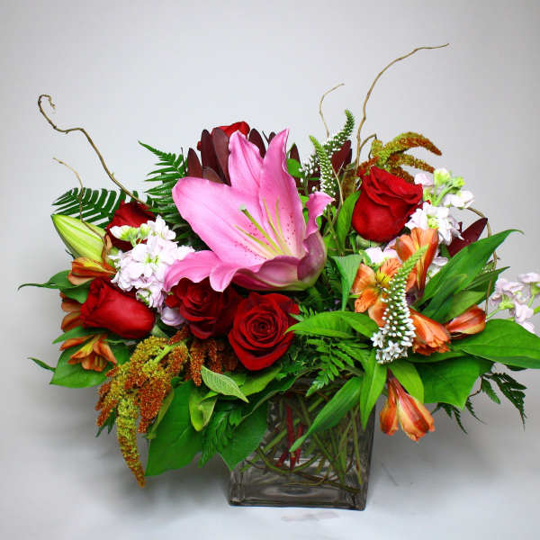 Mixed bouquet with pink lilies and red roses in a glass vase