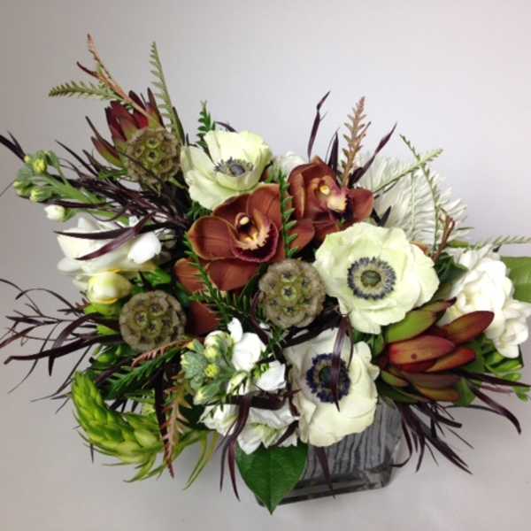 Mixed floral arrangement with white and rust blooms in a square vase