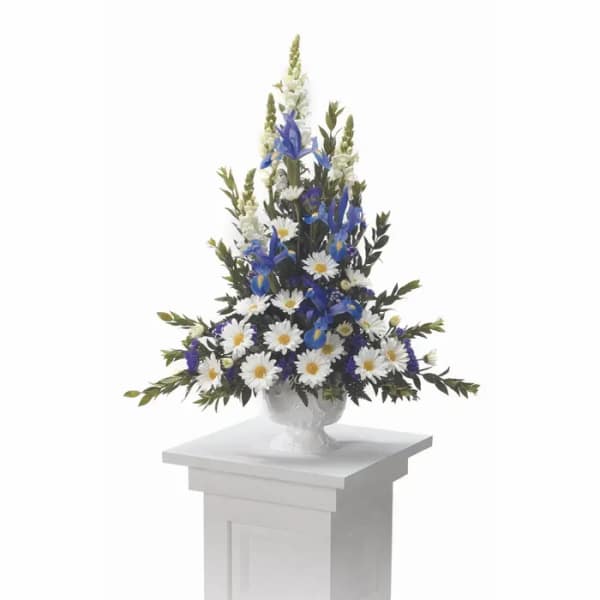 Tall blue and white floral arrangement in a white urn