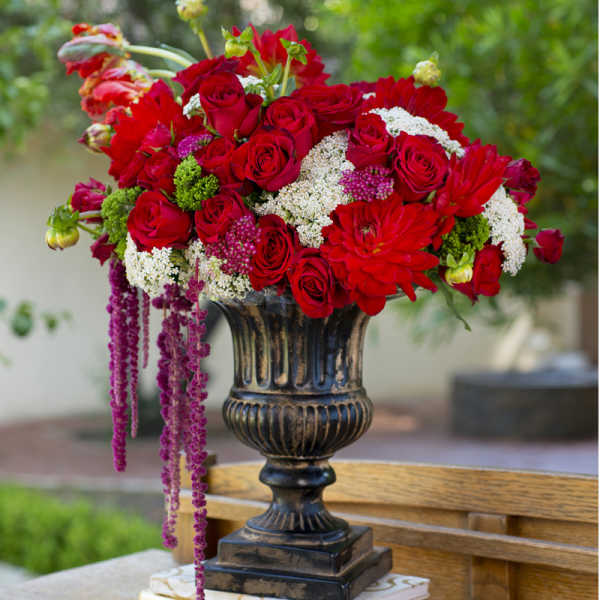 Red roses and dahlias arranged in a dark urn vase