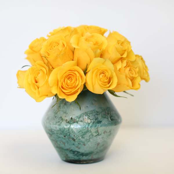 Yellow roses in a green glass vase