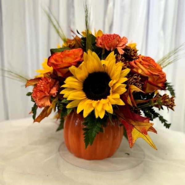 Sunflower and orange floral arrangement in a pumpkin container