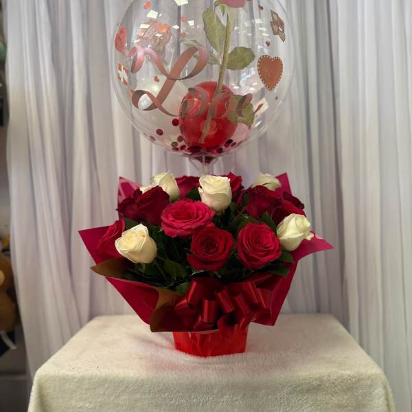 Red and white roses in red wrapping with a heart balloon above