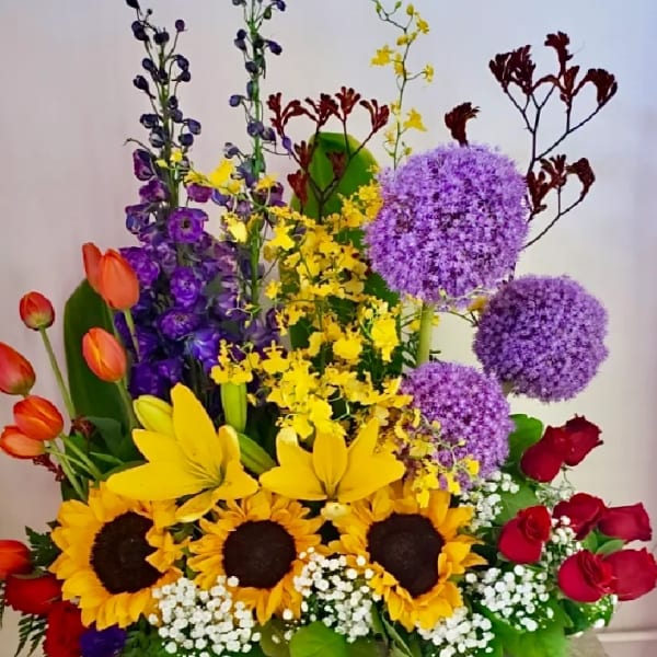 Colorful mixed flower arrangement with sunflowers, roses, tulips, and purple alliums