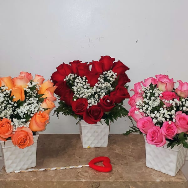 Three rose arrangements in white square vases with a heart decoration