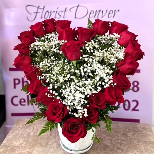 Heart-shaped bouquet of red roses and baby's breath in a white vase