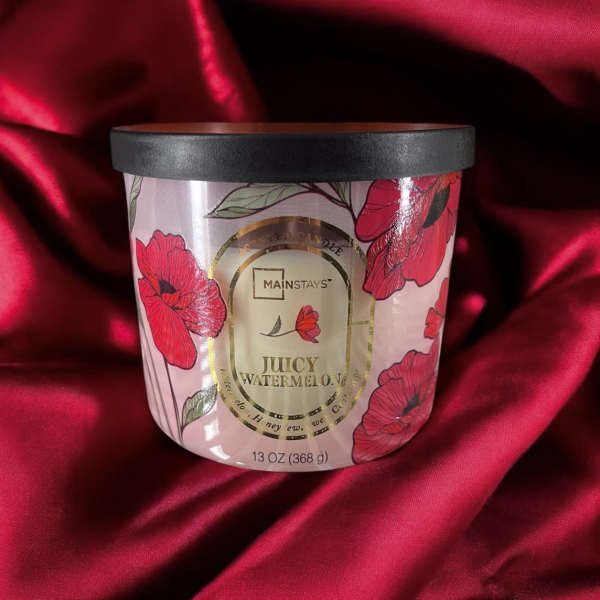 A floral-scented candle in a pink jar with a black lid