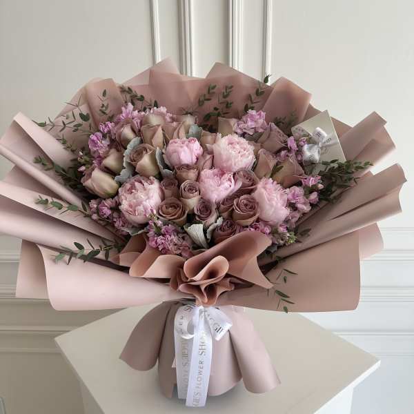 Pink and mauve bouquet of roses and peonies wrapped in blush paper