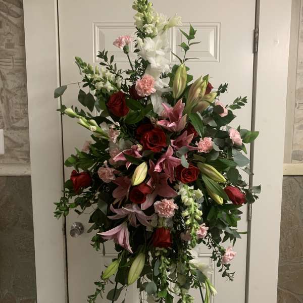Standing floral spray with red roses, pink lilies, and white snapdragons