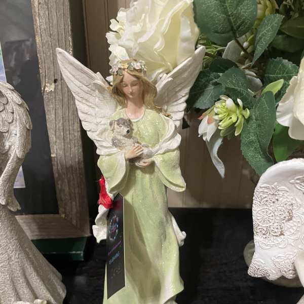 A decorative angel figurine in a pale green dress holding a small animal