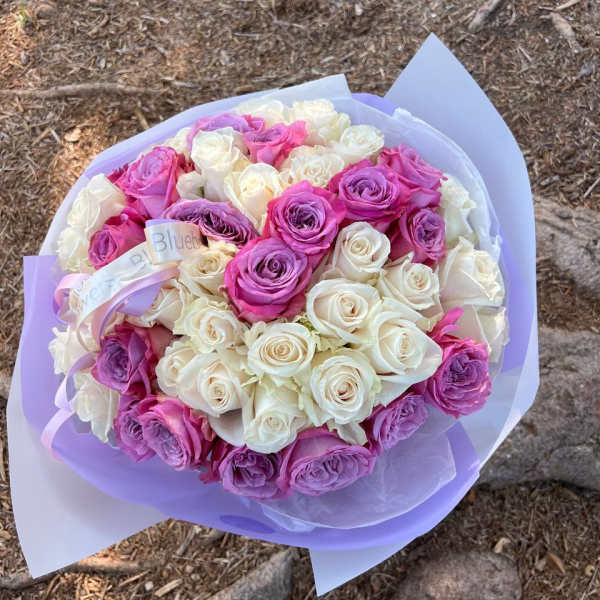 Bouquet of pink, purple, and white roses wrapped in lavender paper