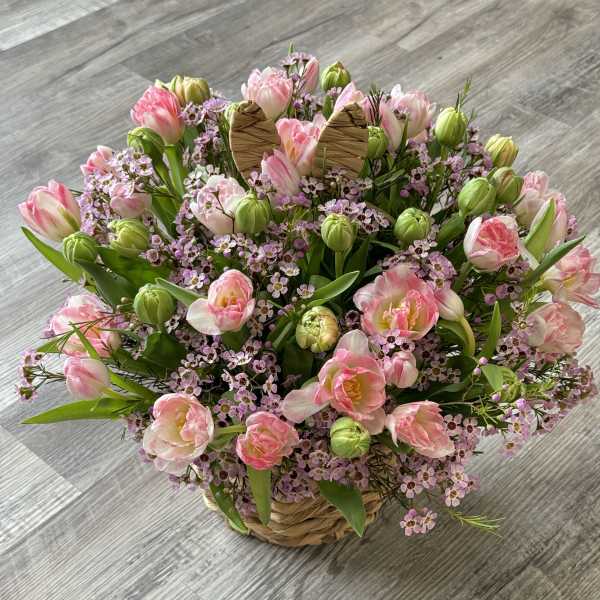 Pink tulips and small lavender flowers in a woven basket