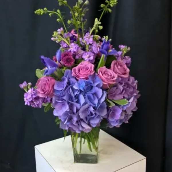 Purple and pink floral arrangement in a clear glass vase