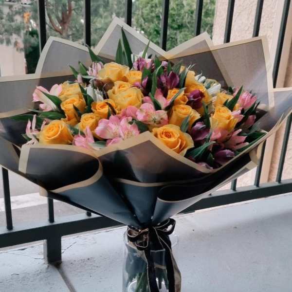 Bouquet of yellow roses and pink flowers in a glass vase