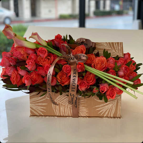 Coral rose bouquet with calla lilies in a patterned gift box