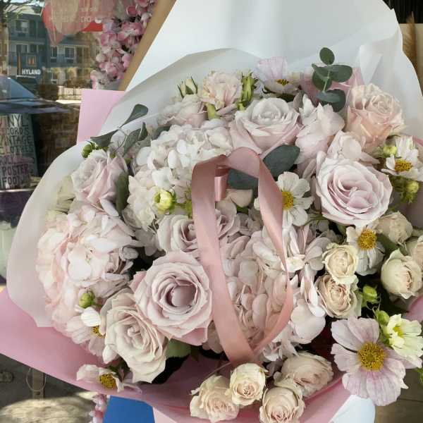 Bouquet of pale pink roses and white flowers wrapped in pink paper