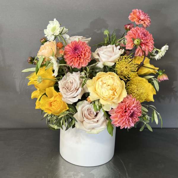 Mixed bouquet of pink, yellow, and white flowers in a white box