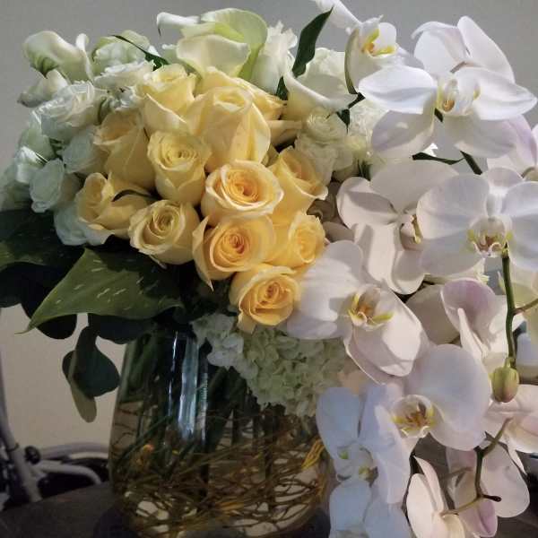 Bouquet of pale yellow roses and white orchids in a glass vase