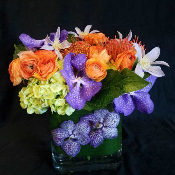 Colorful bouquet in a clear glass vase with orange, purple, and white blooms